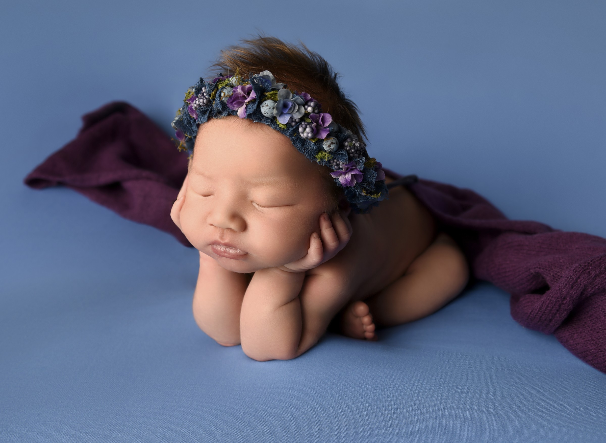 Sleeping newborn with a blue and purple floral headband