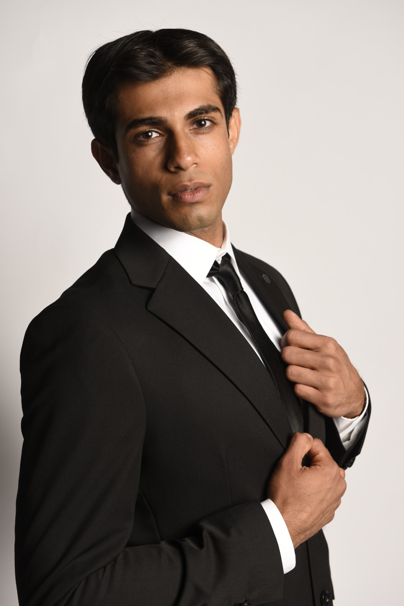 Professional headshot of a man wearing a black suit and tie